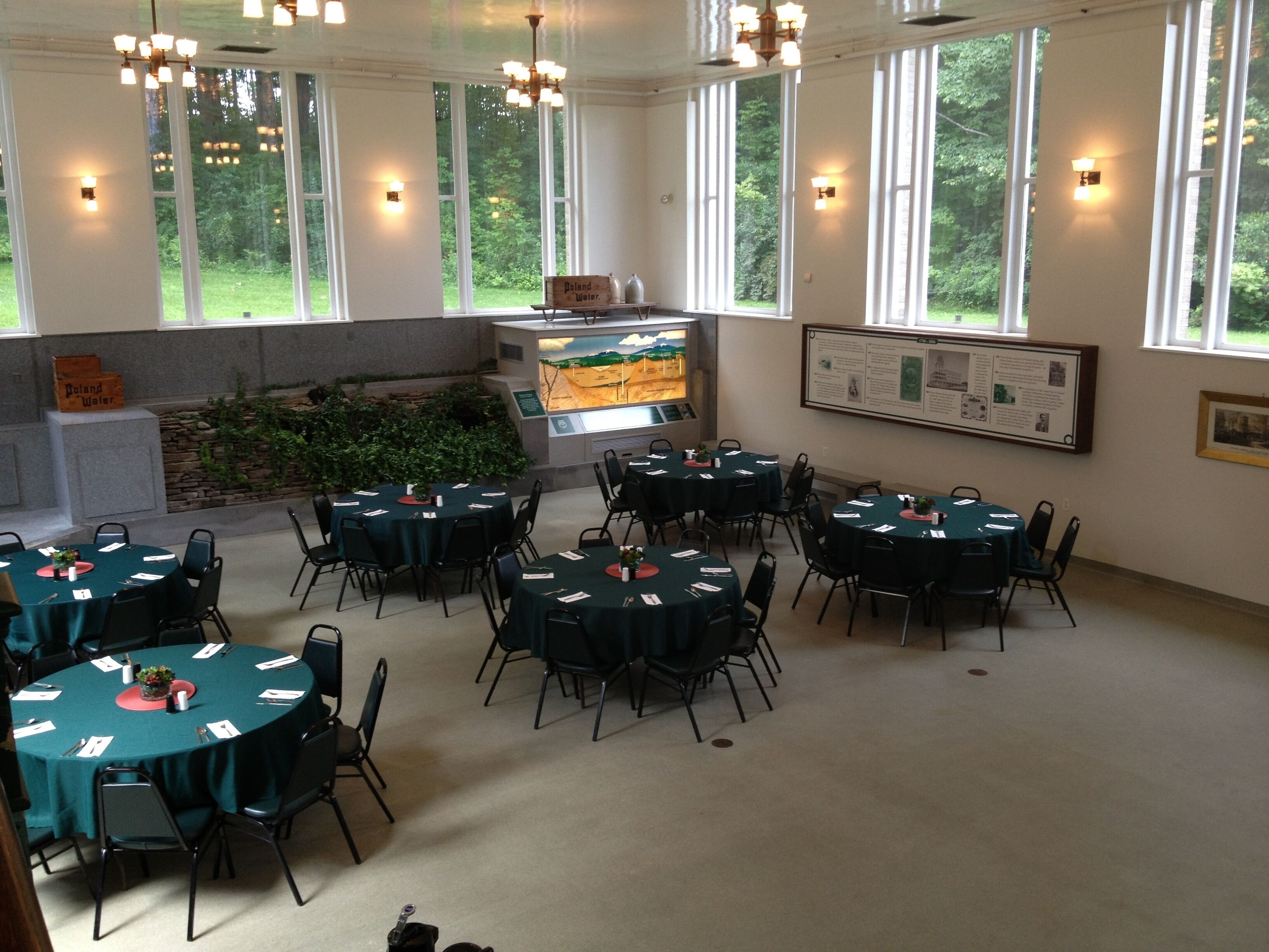 A conference room with round tables, chairs, a display case, and informational posters.
