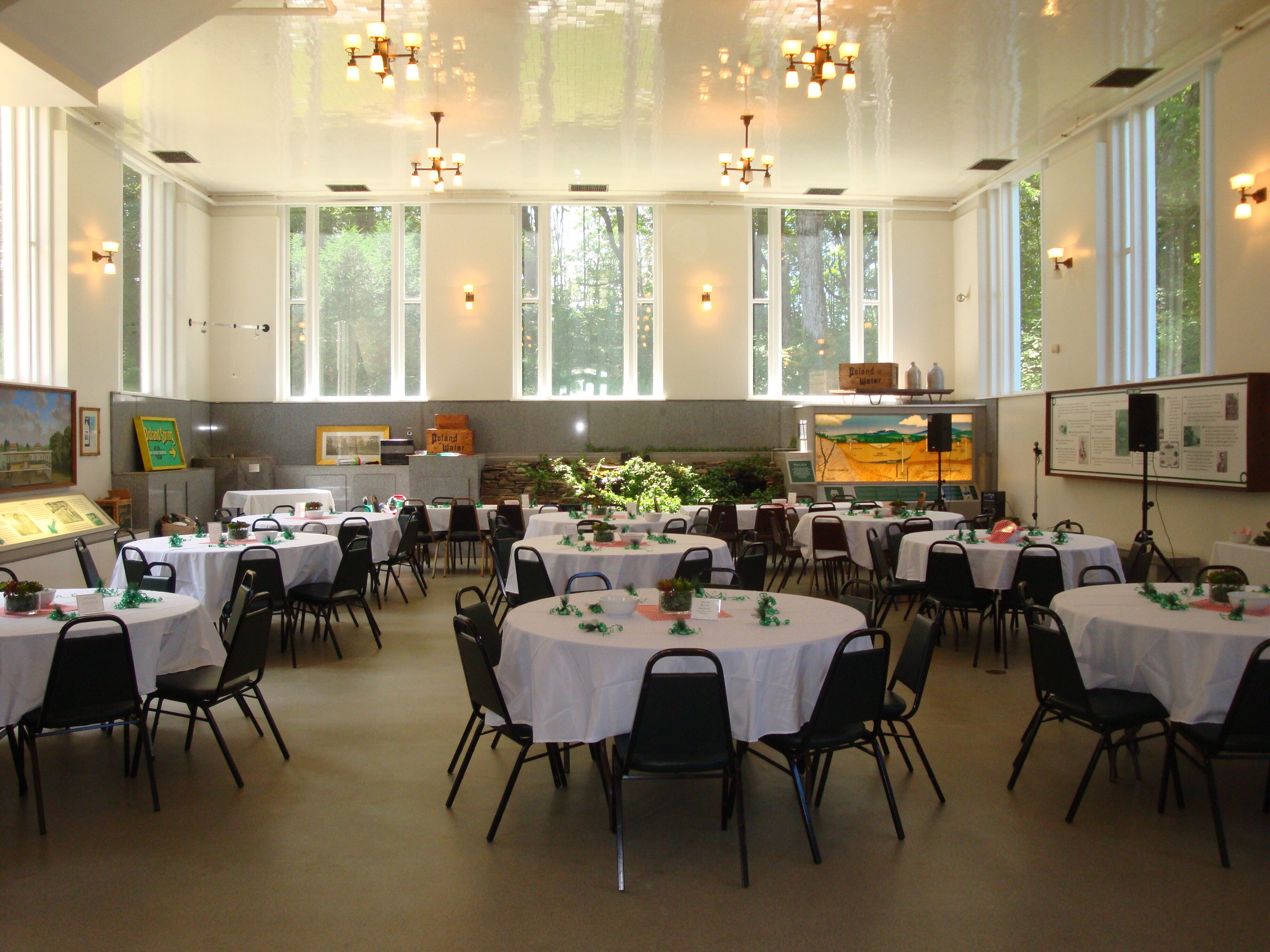 Une salle de conférence dotée de plusieurs tables et chaises, de grandes fenêtres et d’un espace dédié aux présentations, avec un écran de projection.