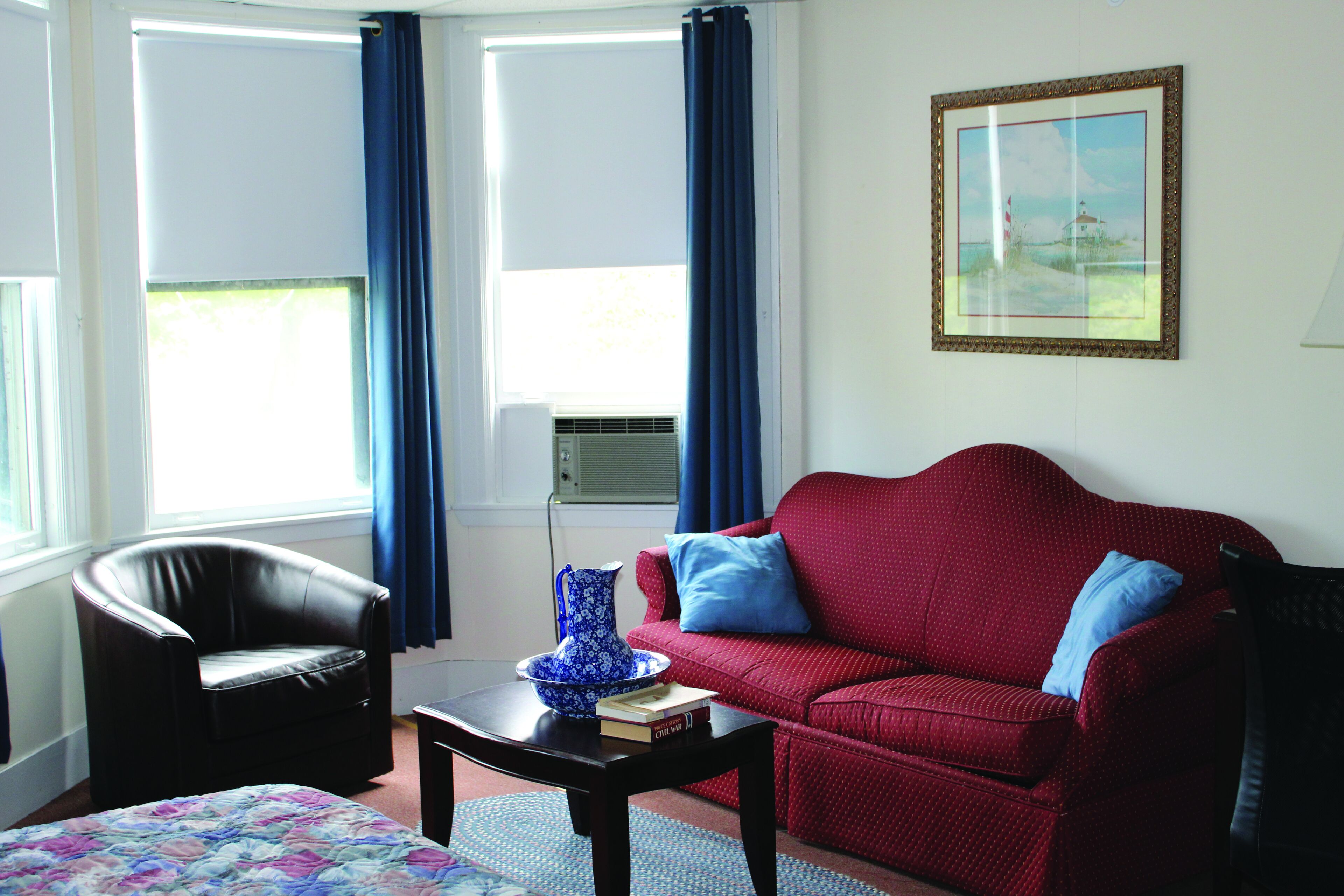 A living room with a red sofa, a black armchair, a coffee table, and a blue vase.