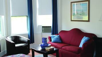 A living room with a red sofa, a black armchair, a coffee table, and a blue vase.