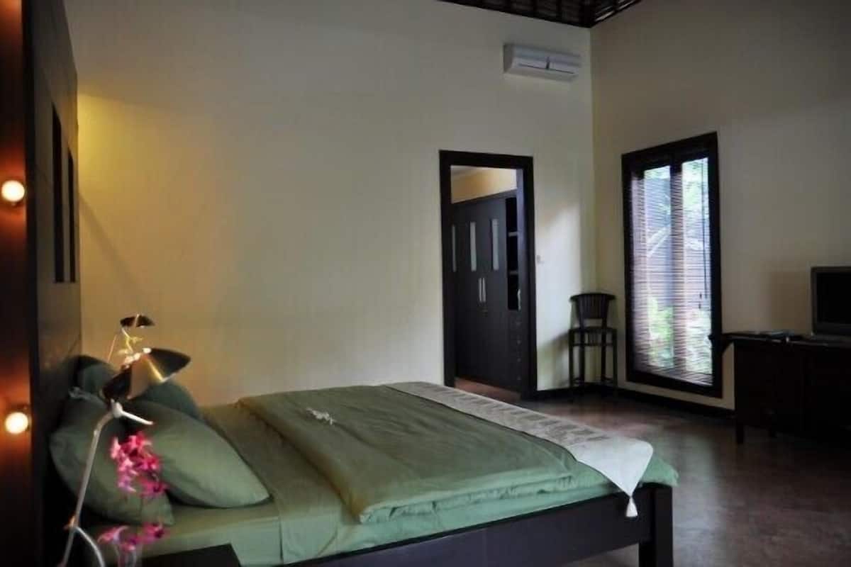 Een slaapkamer met een bed, een stoel, een bureau en een raam met zonwering.