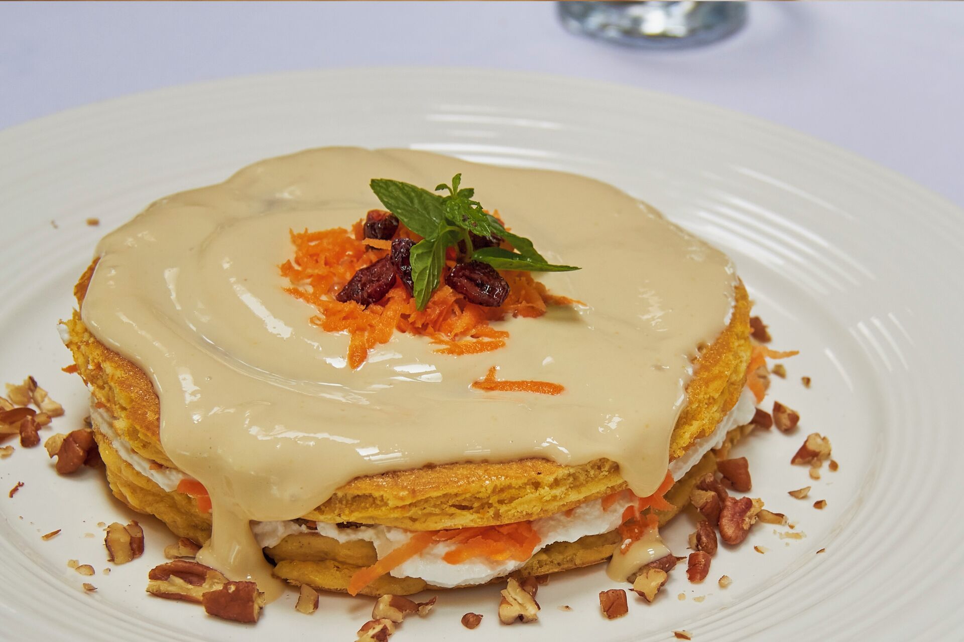 A dessert on a white plate with a creamy topping, garnished with mint and dried fruits.
