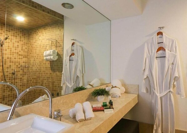 Un baño moderno con un espejo grande, un lavabo y dos batas blancas colgadas de ganchos.