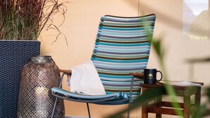 A striped lounge chair with a towel, a metal vase, and a mug on a small table. - Seehotel Kastanienbaum (Horw)