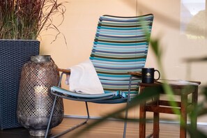 A striped lounge chair with a towel, a metal vase, and a mug on a small table. - Seehotel Kastanienbaum (Horw)