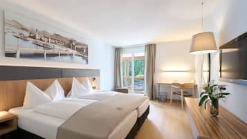 Ein Hotelzimmer mit Bett, Schreibtisch, Stuhl, Fernseher und einem Fenster mit Vorhängen.