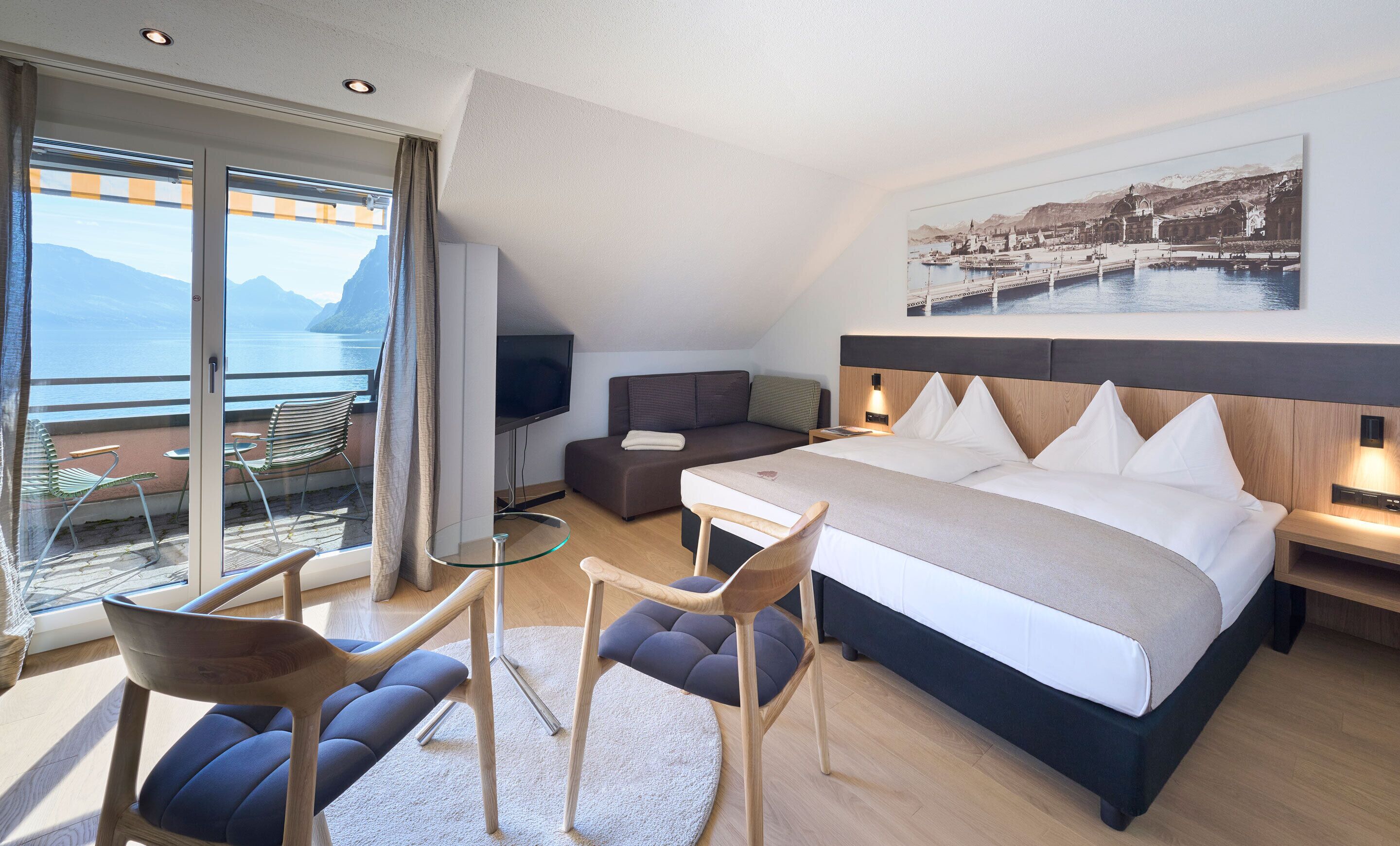 Ein modernes Hotelzimmer mit Bett, Schreibtisch, Fernseher und einem Balkon mit Meerblick.