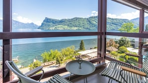 A balcony with a view of a lake and mountains, a chair, a small table, and a railing. - Seehotel Kastanienbaum (Horw)