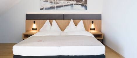 A bedroom with a large bed, two bedside tables, and a headboard with integrated lighting.