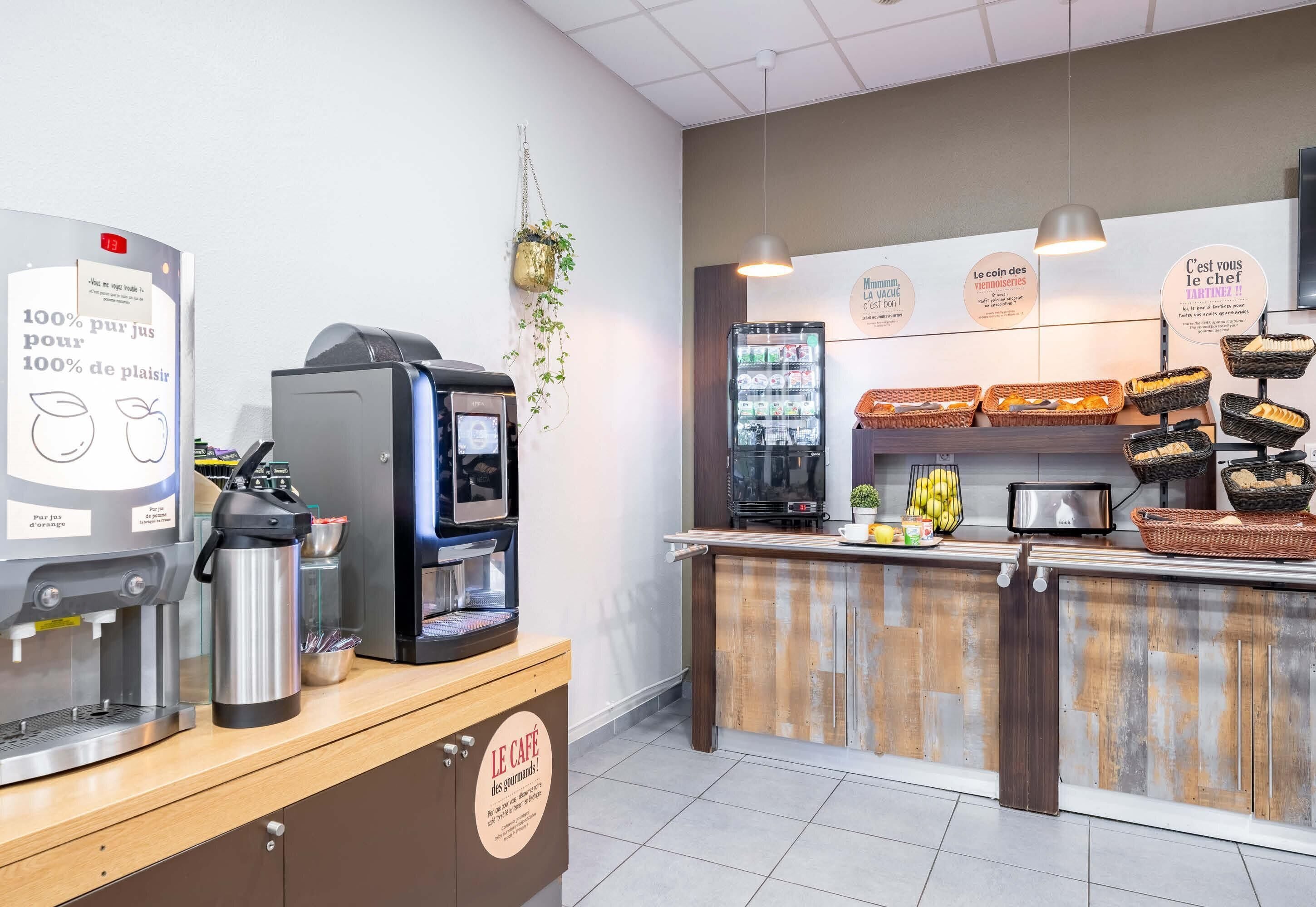 A café with a coffee machine, a refrigerator, and a counter with baskets of bread and bananas.
