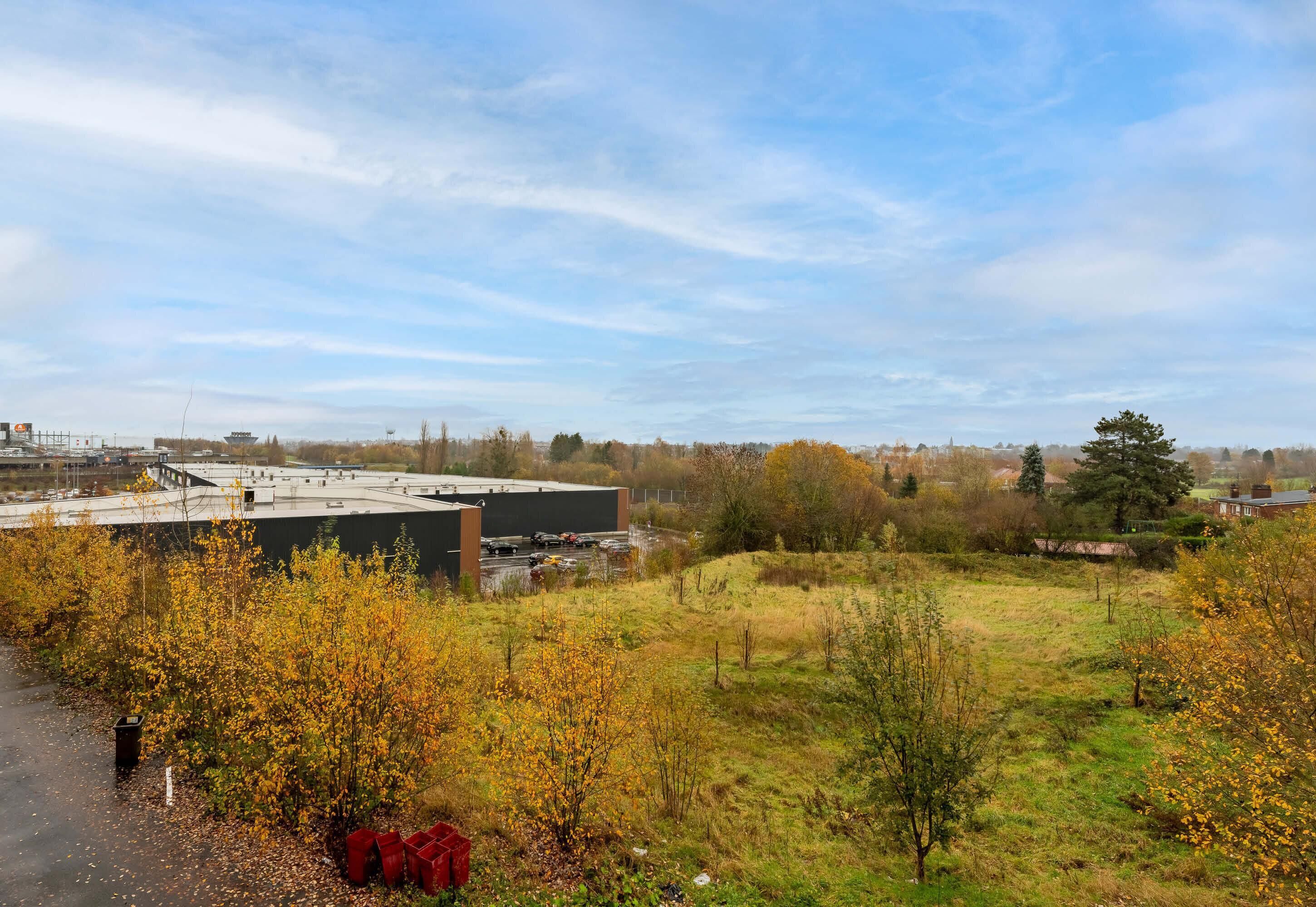A building with a flat roof, surrounded by a grassy area with trees and a clear sky.