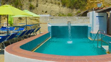 Una piscina al aire libre, sombrillas, sillones reclinables de piscina