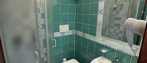 Un baño con cabina de ducha de vidrio, inodoro y lavamanos.