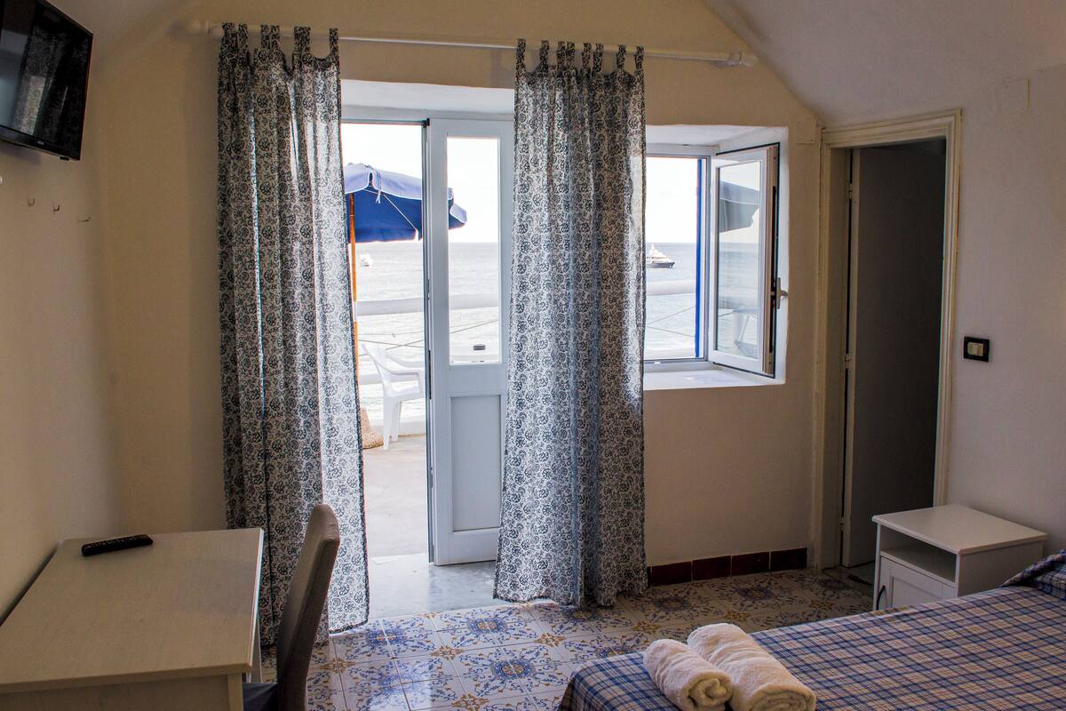 Une chambre avec un lit, un bureau et une fenêtre avec des rideaux.