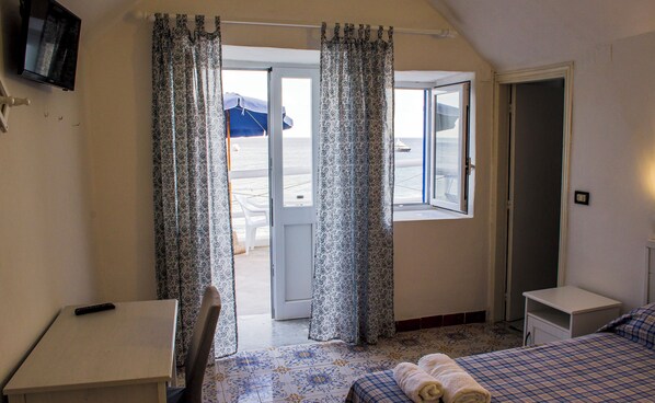 A room with a bed, a desk, and a window with curtains.