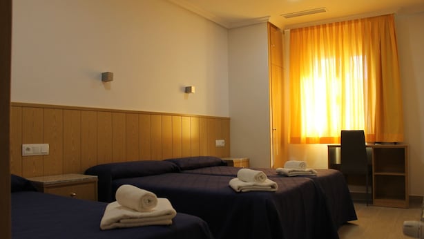 A hotel room with two beds, a desk, and a chair. - Hostal Conchita Legazpi (Madrid)