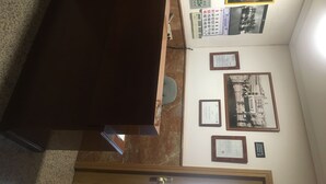 A room with a dark brown sofa, a telephone, a bulletin board with various notices, and framed pictures on the wall. - Hostal Conchita Legazpi (Madrid)