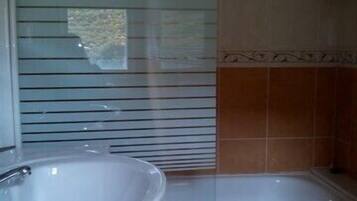 Une salle de bain avec un lavabo, une baignoire et une fenêtre avec des stores.