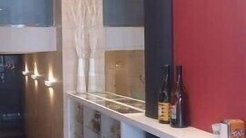Un interior de restaurante con mostrador, un reloj en la pared y una zona de mesas.