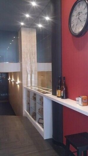 A restaurant interior with a counter, a clock on the wall, and a seating area. - Hotel Muradana (Muros)