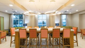 Una sala de conferencias con una amplia mesa, varias sillas y vistas al mar a través de amplios ventanales.