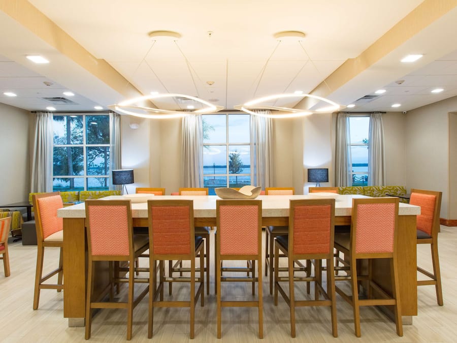 A conference room with a large table, multiple chairs, and a view of the sea through large windows.