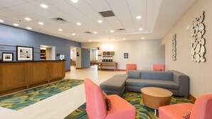 Un hall con mostrador de recepción, zona de estar con sofás y sillones, y alfombra estampada.