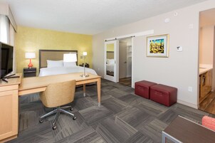 Habitación de hotel con cama, escritorio, silla y armario corredero.