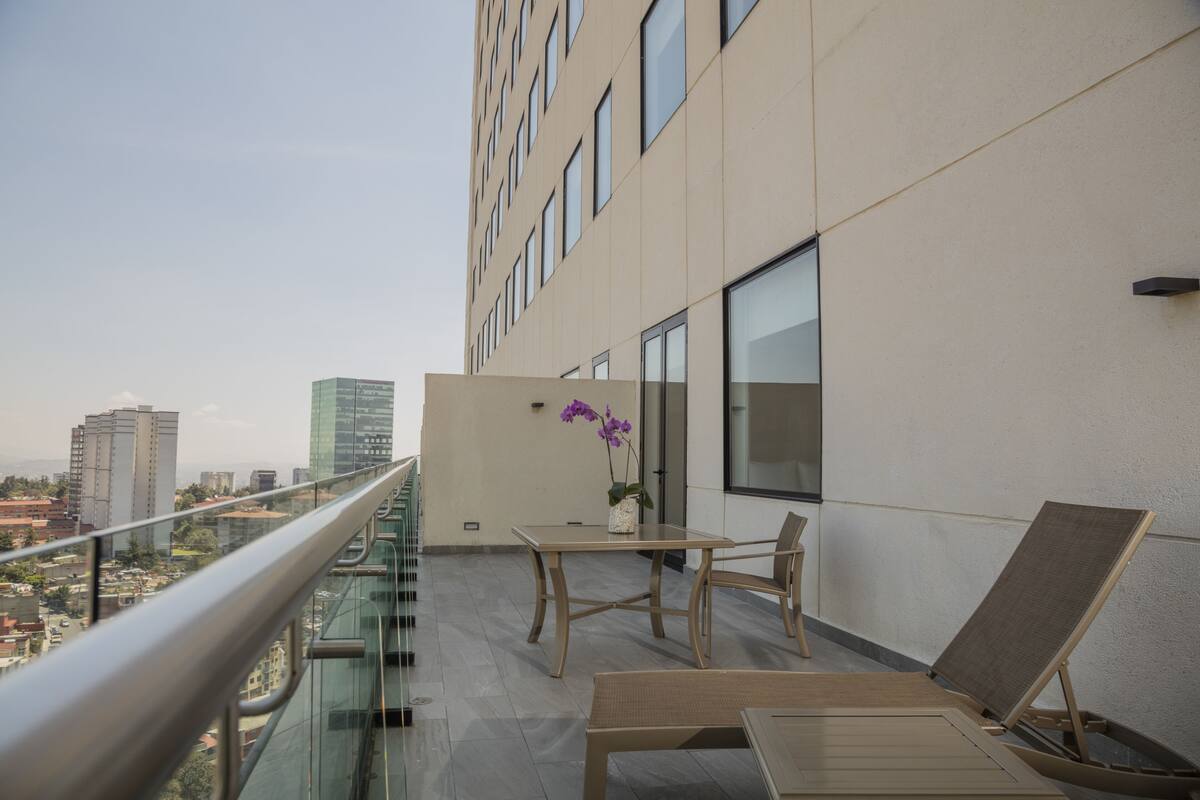 A balcony with a table, chairs, and a flower vase.