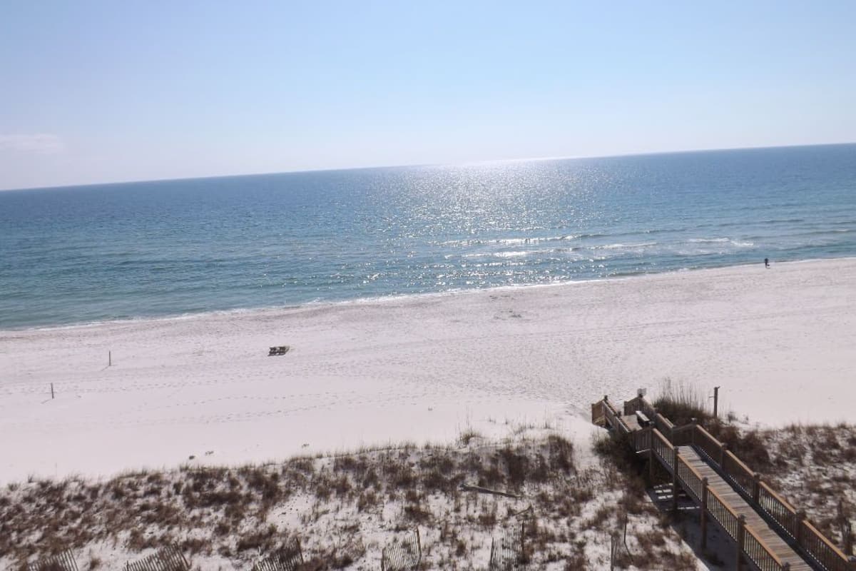 Ein Strand mit einer Holzpromenade, die zum Wasser führt.