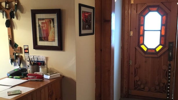 Un interior de fusta amb una taula de recepció, quadres emmarcats i una porta decorativa amb vitrall.