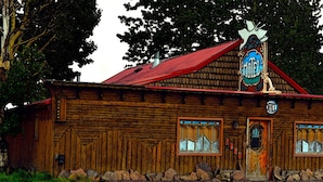 Un edifici de fusta rústic amb teulada vermella, un senyal que indica que és un hotel i una torre de campanars.