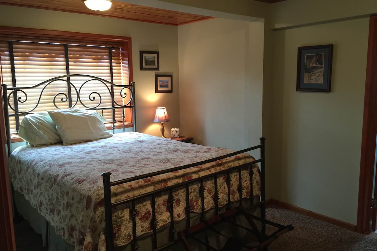 A bedroom with a bed, a nightstand, a lamp, and framed pictures on the wall.