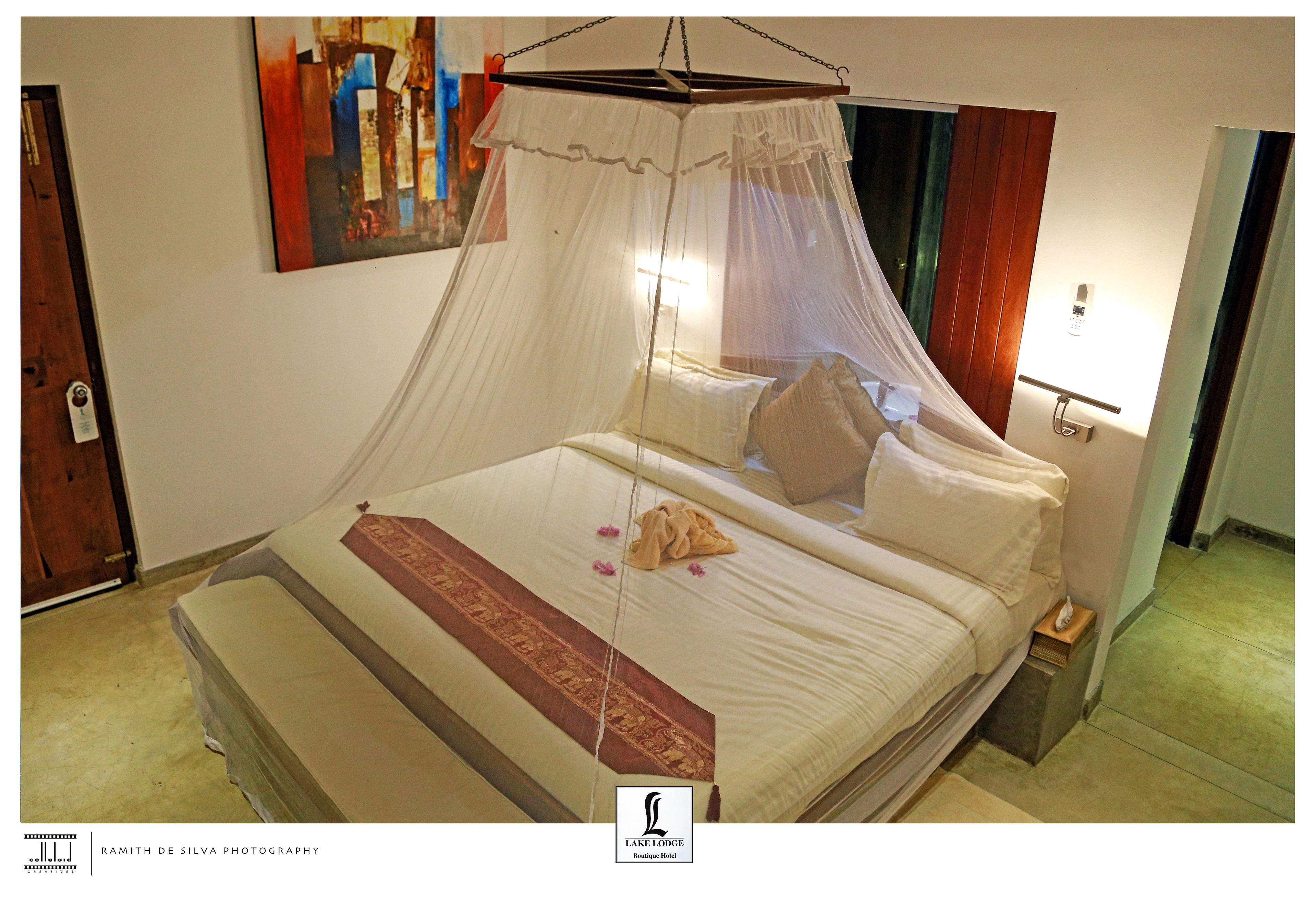 A hotel room with a bed, a nightstand, a bedside lamp, and a painting on the wall.