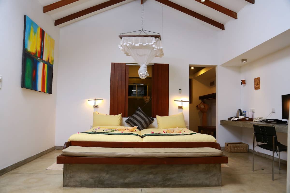 Quarto com uma cama grande, luminárias de cabeceira, uma escrivaninha e uma cadeira.
