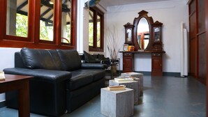 A living room with a black leather sofa, a wooden table, and a mirror above a wooden cabinet.