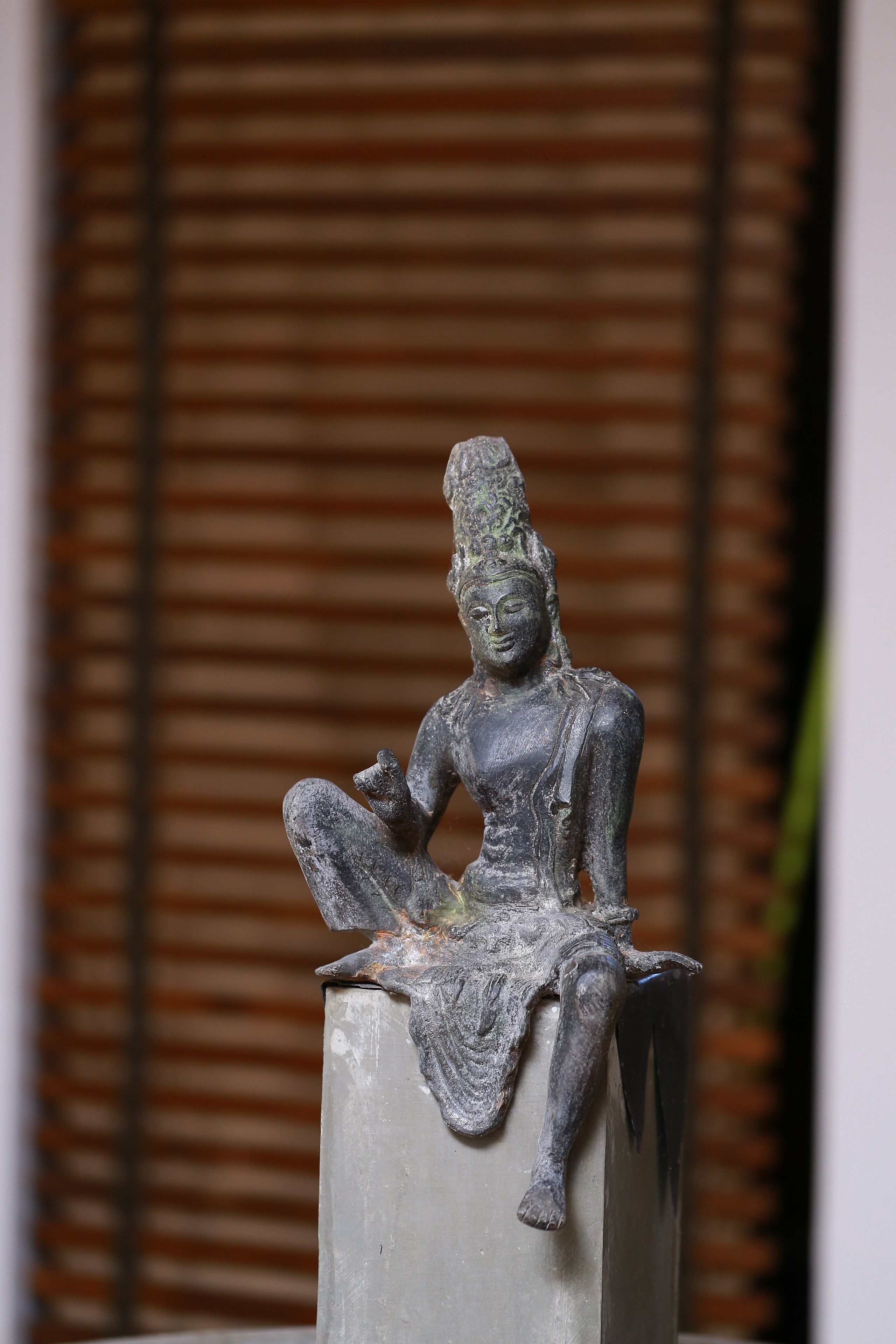 Uma estátua de uma figura sentada sobre um pedestal.