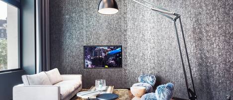 Un salon moderne avec un canapé, une table basse, un lampadaire et un téléviseur fixés sur un mur à texture.