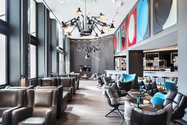 Un espace lounge moderne avec des fauteuils en cuir, un bar et un grand écran de télévision.