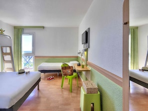A hotel room with a bed, a desk with a chair, a television, and a window with curtains. - ibis budget Cannes Mougins (Mougins)