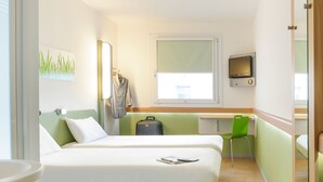 A hotel room with two beds, a desk, a chair, a suitcase, and a TV. - ibis budget Cannes Mougins (Mougins)