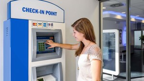 A woman using a check-in point with a digital interface, a card reader, and a cash slot. - ibis budget Cannes Mougins (Mougins)