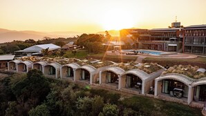 A resort with a pool, outdoor seating, and a view of the sunset.