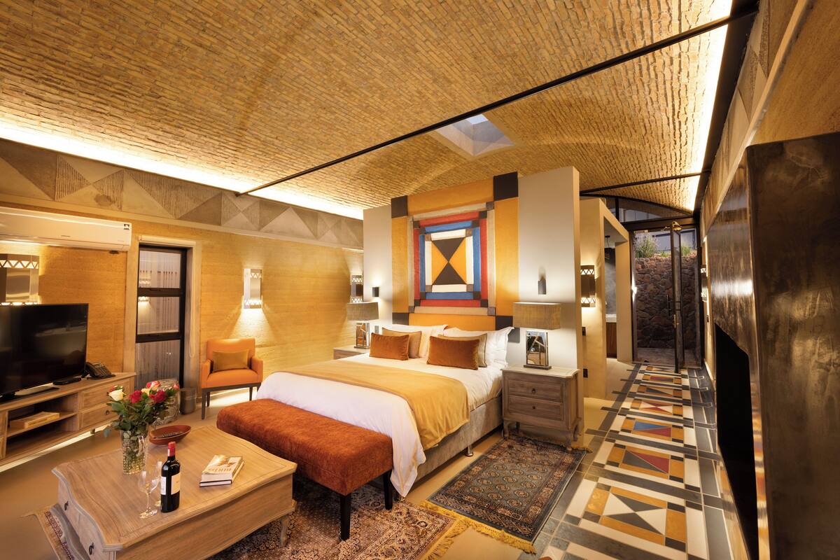 Una habitación de hotel moderna con una cama grande, televisión, escritorio y vistas al exterior.