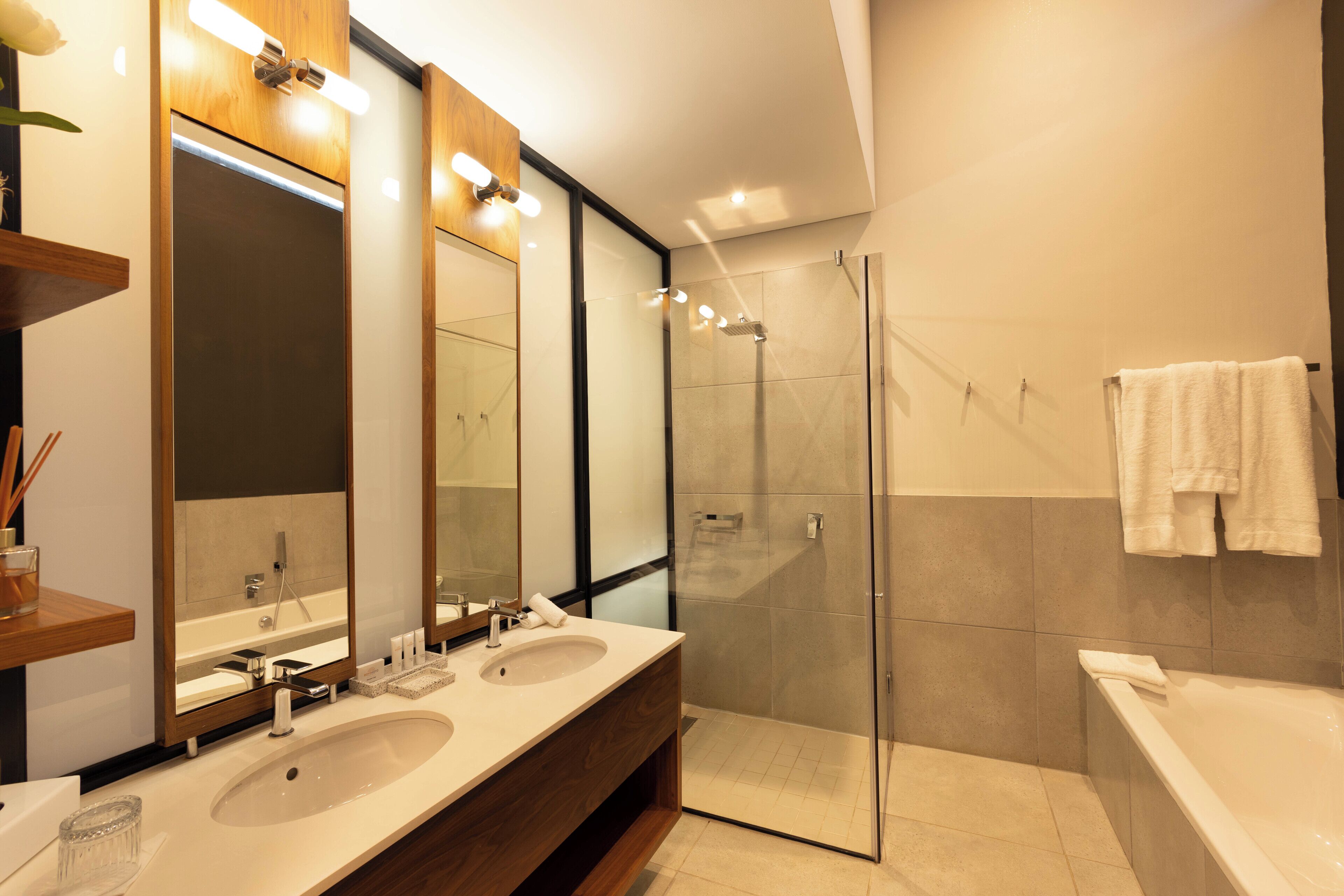 A modern bathroom with two sinks, a glass shower enclosure, and a bathtub.