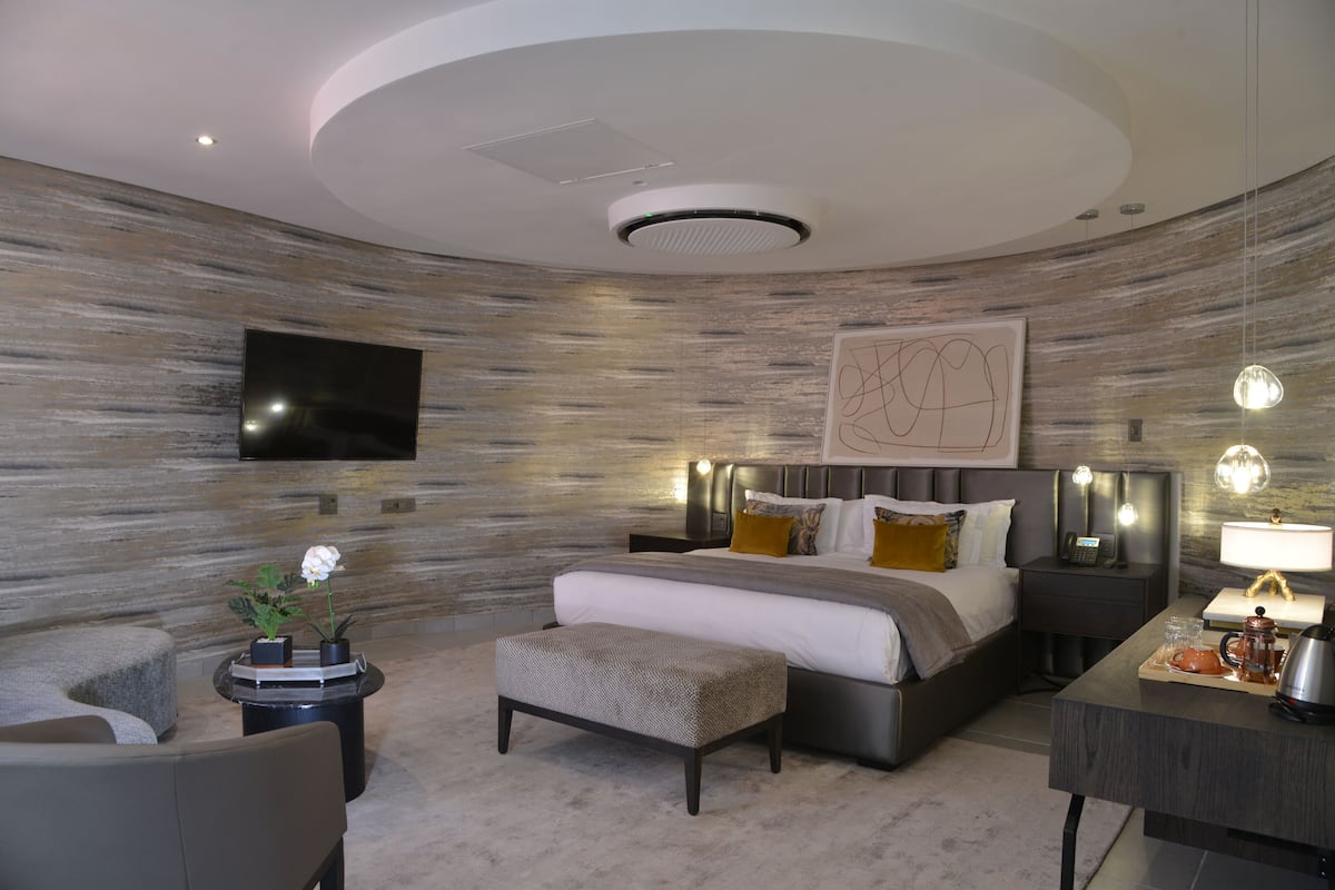 Un dormitorio moderno con una cama grande, mesitas de noche, un televisor de pantalla plana y un elemento decorativo en la pared.