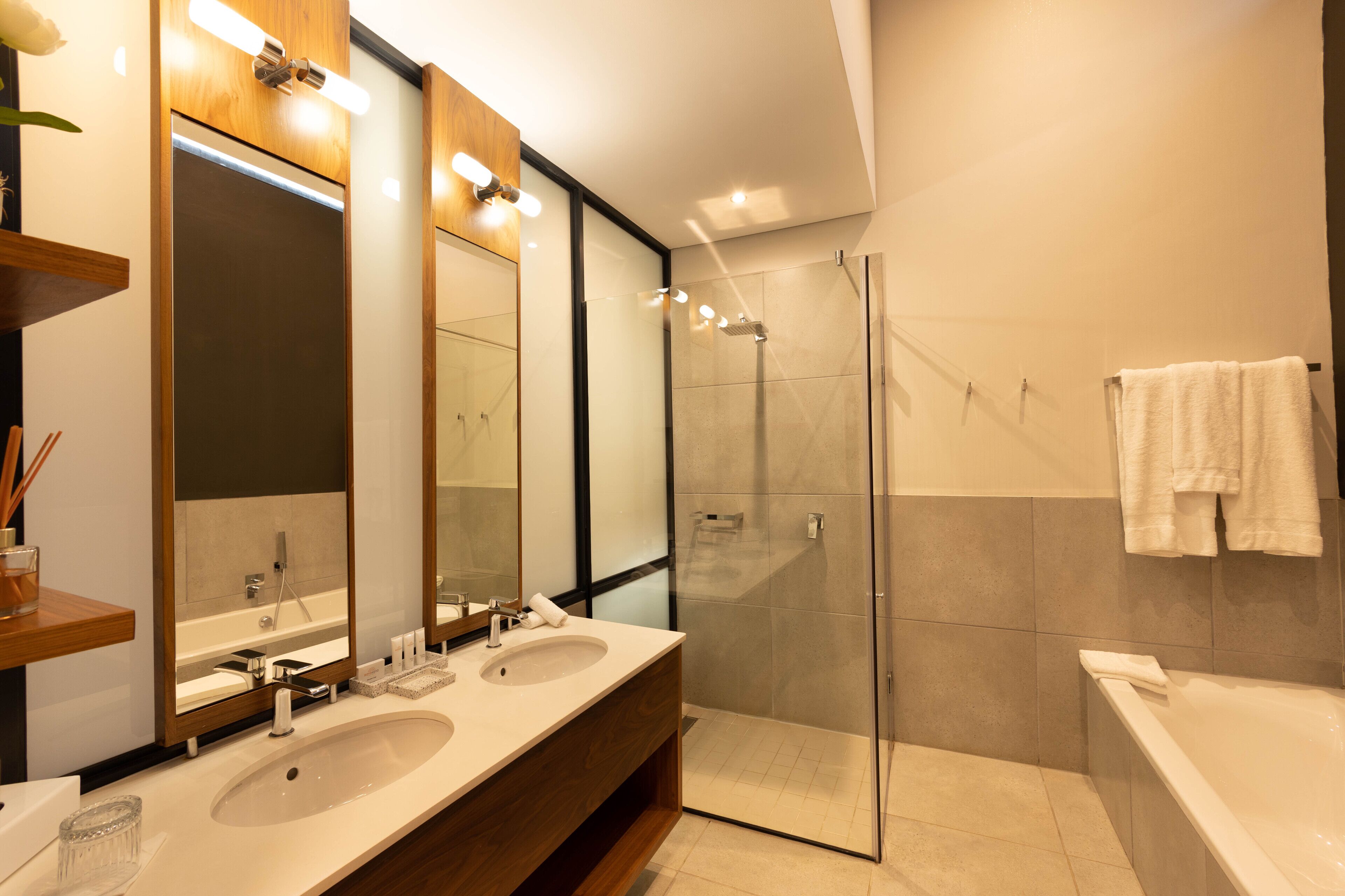 Un baño moderno con dos lavamanos, una cabina de ducha de vidrio y una bañera.