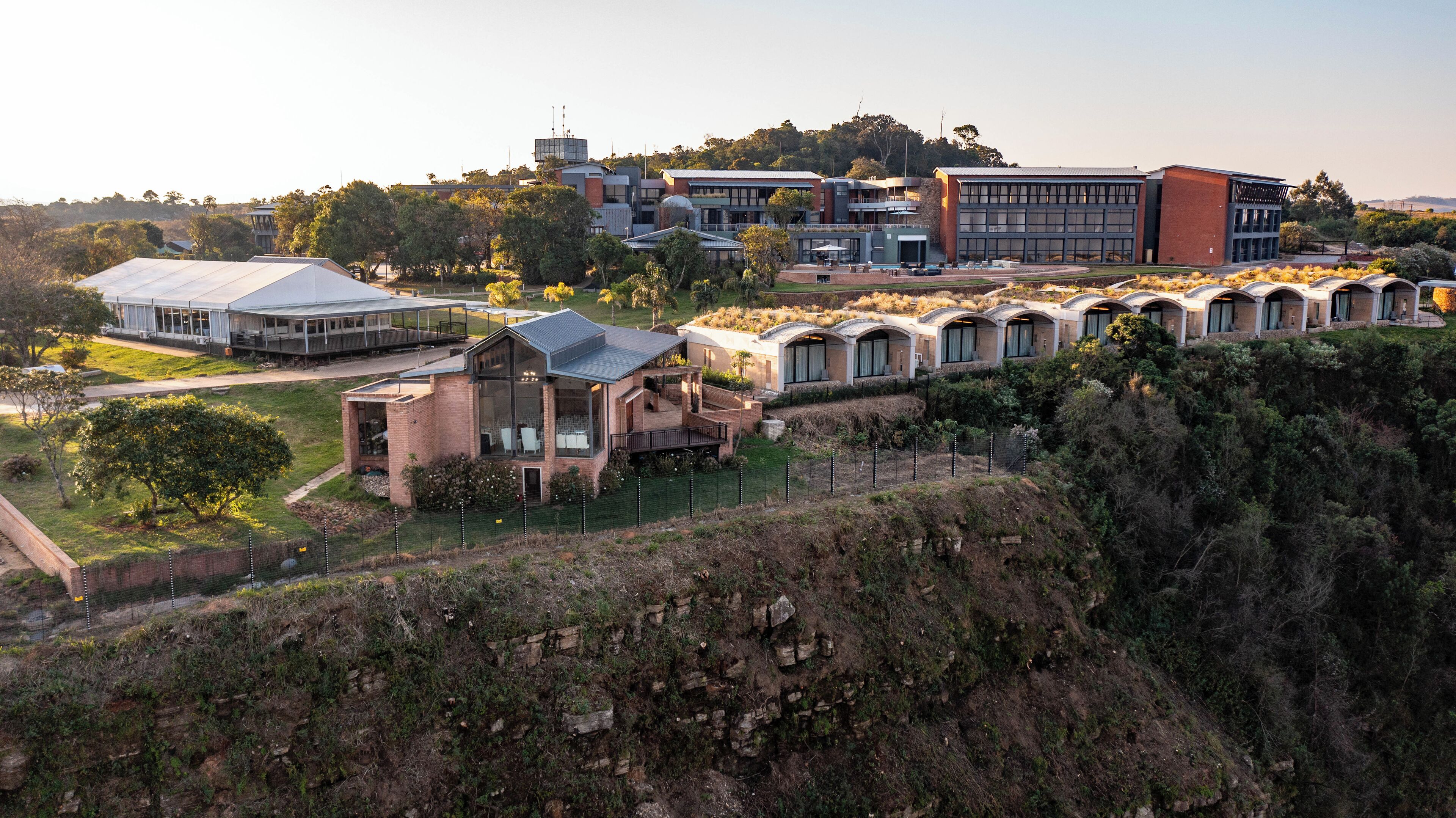 A modern building complex with multiple structures, including a large glass-roofed building and several smaller units with arched roofs.