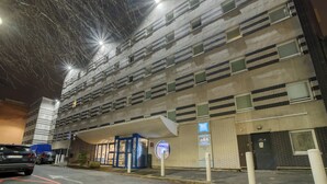 A multi-story parking garage with a covered entrance and a sign indicating a nearby business.