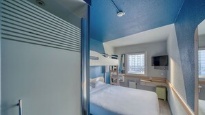A modern bedroom with a bed, a desk, a chair, and a TV.